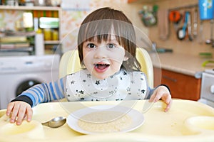 Little child age of 2 years eats wheat porridge with pumpkin