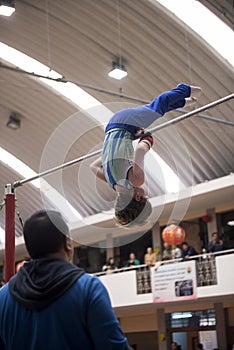 Little child athletic gymnast performing exercises at the bar in the championship