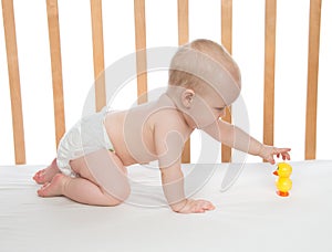 Little child baby girl crawling in bed with toy duck