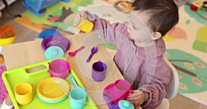little child baby girl playing with plastic toy tea cups