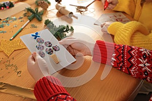 Little child with beautiful Christmas greeting card at wooden table, closeup