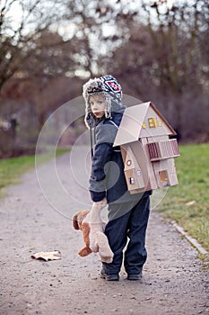 Little child, blond boy with pet dog, carying home on his back, kid, having paper house