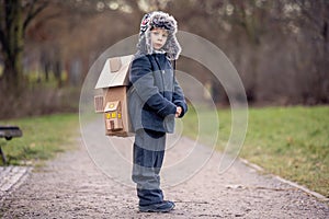 Little child, blond boy with pet dog, carying home on his back, kid, having paper house