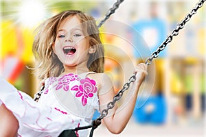 Little child blond girl having fun on a swing