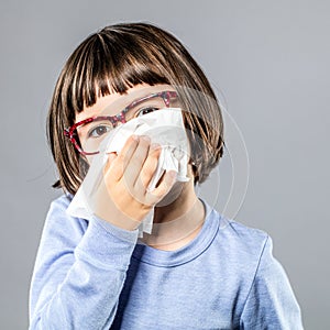 Little child blowing nose in tissue for cold or allergies