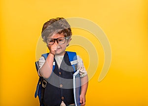 Little child boy with book and bag isolated on yellow. Smiling kid go back to school, kindergarten. Success, motivation