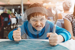 Little child boy hungry waiting for dinner in restaurant