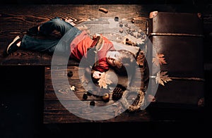 Little child boy lies on a warm blanket dreams of warm autumn. Kid playing in autumn. Little cute boy lies on a wooden