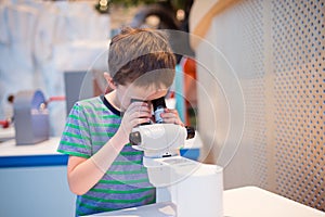 Little child boy looking through microscope