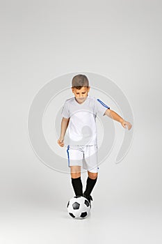 Little child boy in outfit play with soccer ball