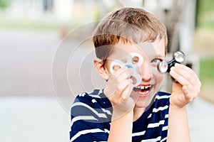 Little child boy playing with fidget spinner outdoors