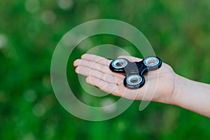 Little child boy playing with fidget spinner outdoors