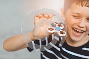 Little child boy playing with fidget spinner outdoors