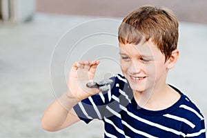 Little child boy playing with fidget spinner outdoors