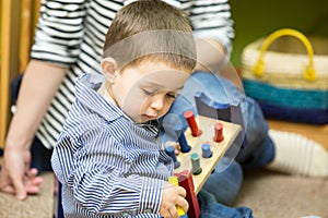Little child boy playing in kindergarten in Montessori Class.