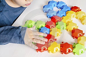 Little child boy playing with mosaic constructor.Babys hands building figures of plastic blocks.Children logic,fine motor skills