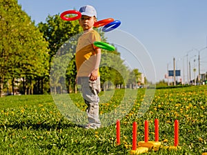 Little child boy playing. Ring throw summer game on a green lawn in the sun