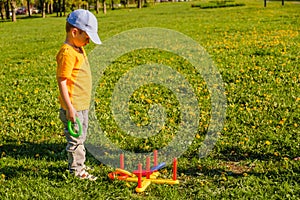 Little child boy playing. Ring throw summer game on a green lawn in the sun