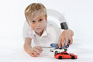 Little child boy playing satisfyingly with his toys and building a tower of the cars