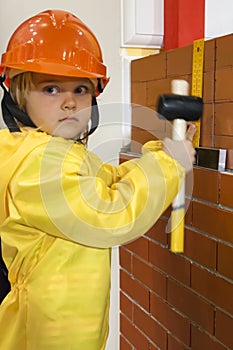 Little child builder in hardhat with hammer