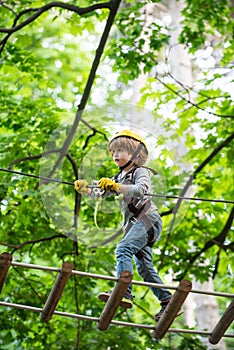 Little child climbing in adventure activity park with helmet and safety equipment. Helmet and safety equipment. Children