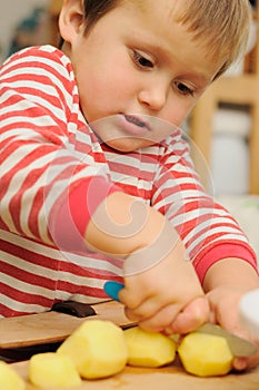 Little child cutting potatoes