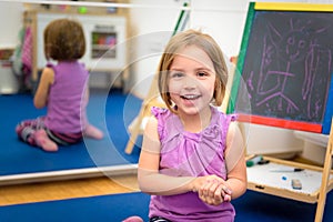 Little child is drawing with color chalk on the chalk board