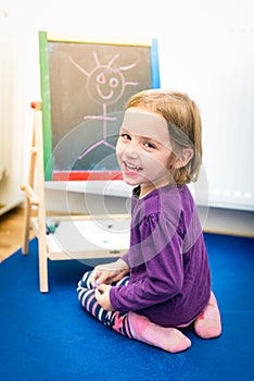 Little child is drawing with color chalk on the chalk board