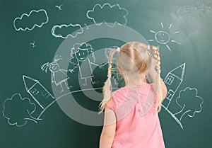 Little child drawing family with white chalk