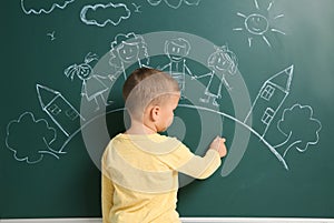 Little child drawing family with white chalk