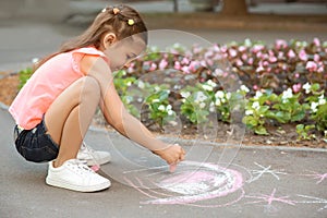 Little child drawing heart with chalk