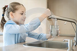 Little child is drinking fresh and pure tap water from glass. Water being poured into glass from kitchen tap. Zero waste and no