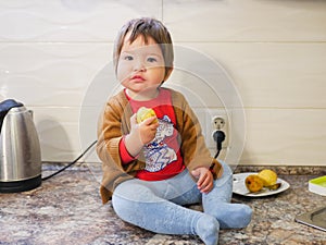 Little child eats a pear. child boy eating fruits at a high stoic. in the kitchen