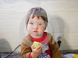 Little child eats a pear. child boy eating fruits at a high stoic. in the kitchen