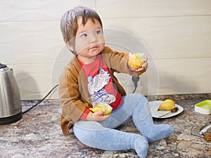 Little child eats a pear. child boy eating fruits at a high stoic. in the kitchen