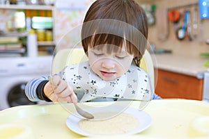 Little child eats wheat porridge with pumpkin