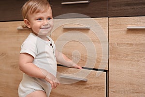 Little child exploring drawer indoors. Dangerous situation