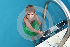 Little child getting out of  swimming pool. Dangerous situation