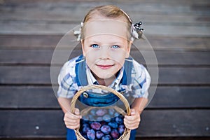 Little child girl with basket full of plums