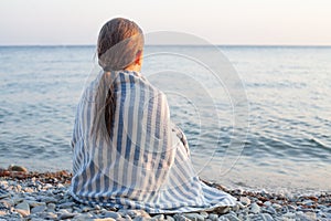 Little child girl in blue and white striped towel relaxing on the sea beach