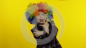 Little child girl clown in colorful wig making silly faces, having fun, smiling, dancing. Halloween