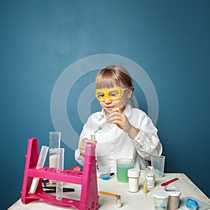 Little child girl doing a chemistry experiment in science class