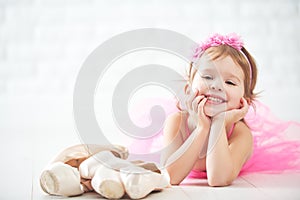 Little child girl dreams of becoming ballerina with ballet shoe