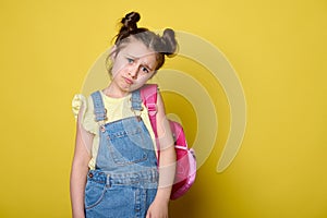 Little child girl, elementary school student with pink backpack, looking at camera with sad, unhappy and sorrowful gaze.