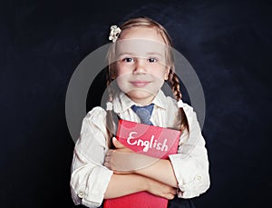 Little child girl embracing english book against chalkboard