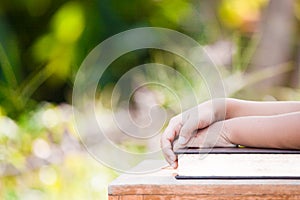 Little child girl hands folded on book in outside