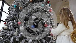 Little child girl helping decorate Christmas tree using toys