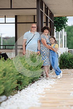 Little child girl hugs grandparents On Walk in the summer outdoors. Concept of friendly family