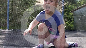 A Little child girl jumping on the trampoline in the back yard