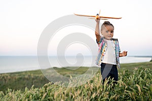 little child girl launches a toy airplane into the sky. baby walks in the field at sunset in summer. childhood and